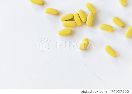 Yellow long vitamins or pills on white background, macro, close-up, copy space. Nutritional supplements concept, health, vitamins, trendy color of 2021, Illuminating. Horizontal 74957900