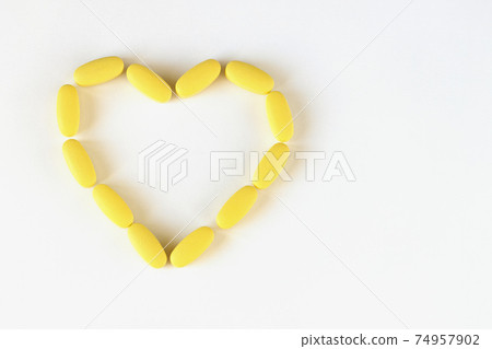 Yellow long pills laid out in shape of heart on white background, macro, close-up, copy space. Nutritional supplements concept, health, vitamins, trendy color of 2021, Illuminating. Horizontal Yellow long pills laid out in shape of heart on white background, macro, close-up, copy space. Nutritional supplements concept, health, vitamins, trendy color of 2021, Illuminating. Horizontal 74957902