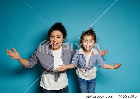 A woman and a girl equally dressed looking at the camera with open arms expressing displeasure and surprise A woman and a girl equally dressed looking at the camera with open arms expressing displeasure and surprise 74958399