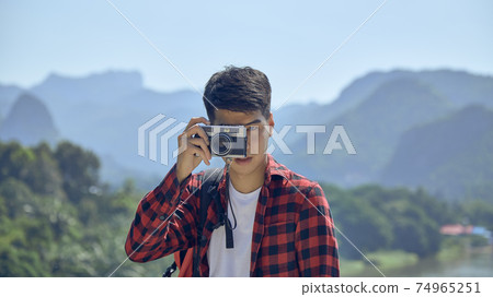 Young man photographing with vintage camera 74965251