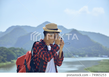 Young man photographing with vintage camera Young man photographing with vintage camera 74965253