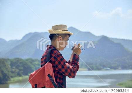Young man photographing with vintage camera 74965254