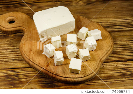Feta cheese on cutting board on a wooden table Feta cheese on cutting board on a wooden table 74966784