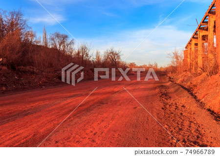 Red dirt road polluted with iron ore near iron ore quarry in Kryvyi Rih, Ukraine 74966789