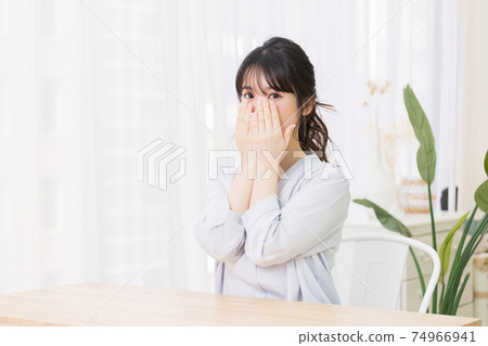 Young woman making a gesture to hide her face in the room 74966941