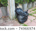 Black garbage bags big and small Completely sealed, are placed on the cement floor. 74966974