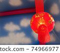 A red lantern hanging on a wooden beam painted in red. Behind the scenes, spraying an airbrush is a picture of white sky and clouds. 74966977
