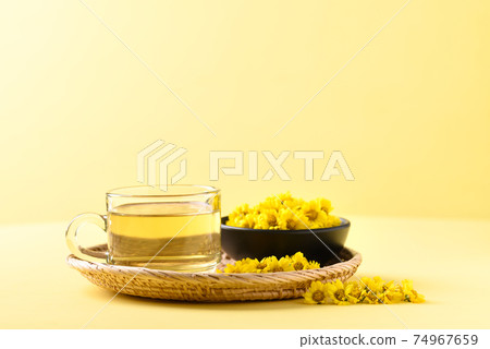 Organic Chrysanthemum flower tea in a cup on yellow background, Healthy Herbal drink 74967659