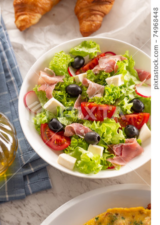 Healthy salad in a bowl with olives, raddishes, tomato, cheese and lean ham served for breakfast Healthy salad in a bowl with olives, raddishes, tomato, cheese and lean ham served for breakfast 74968448