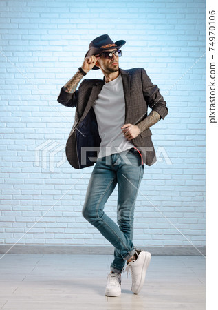 fashionable stylish man in a jacket and a cowboy hat poses in the studio fashionable stylish man in a jacket and a cowboy hat poses in the studio 74970106