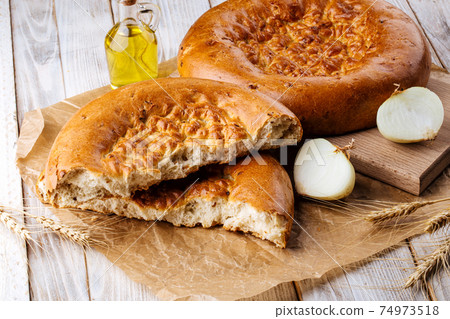 Broken onion flat bread on the wooden background 74973518