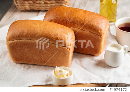 Loafs of white brick shaped bread with butter 74974172