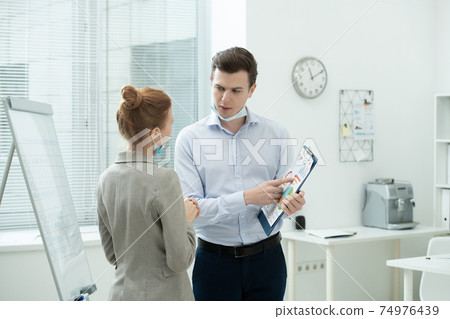 Two young elegant accountants discussing financial data at meeting in office Two young elegant accountants discussing financial data at meeting in office 74976439