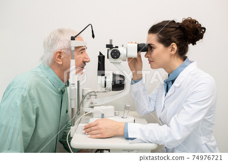 Young brunette female ophthalmologist working with senior patient in clinics 74976721