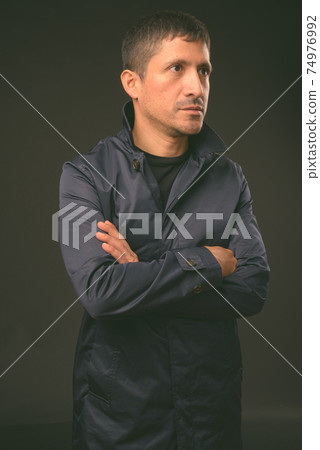 Portrait of Hispanic businessman against black background 74976992