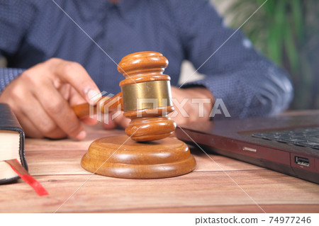close up of person's hand striking the gavel. close up of person's hand striking the gavel. 74977246