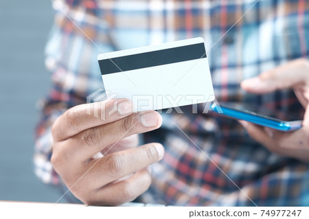 Man hand holding credit card and using smart phone shopping online Man hand holding credit card and using smart phone shopping online 74977247