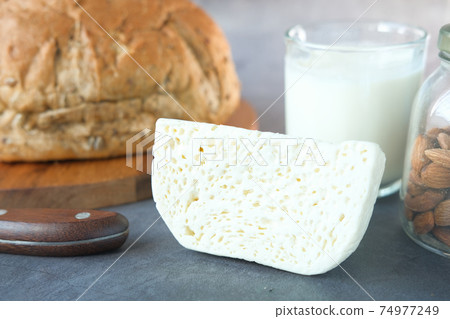 Close up of cheese, milk , brown bread and almond nut on table. Close up of cheese, milk , brown bread and almond nut on table. 74977249