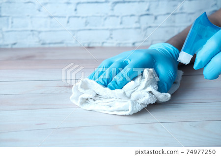 Person hand in disposable gloves using disinfectant spray to clean table surface Person hand in disposable gloves using disinfectant spray to clean table surface 74977250