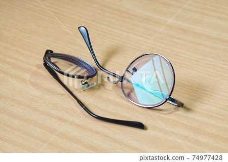 Broken Eye Glasses on the Wood Table in the Morning  74977428