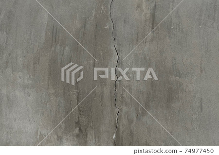 Cracked concrete on grey wall in the middle of frame. Cracked concrete on grey wall in the middle of frame. 74977450