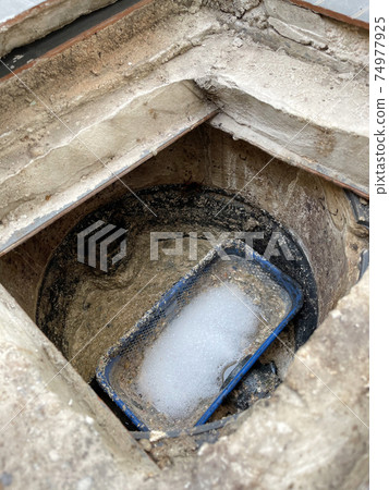 Grease trap plastic box with fatty water floating on top and chemical bubble 74977925