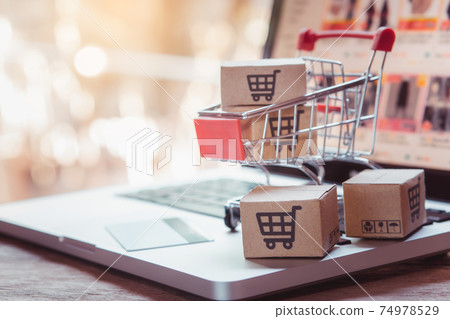 Shopping online. Credit card and cardboard box with a shopping cart logo in a trolley on laptop keyboard. Shopping service on The online web. offers home delivery 74978529