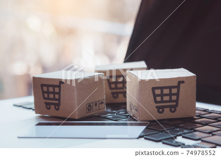 Shopping online. Credit card and cardboard box with a shopping cart logo on laptop keyboard. Shopping service on The online web. offers home delivery Shopping online. Credit card and cardboard box with a shopping cart logo on laptop keyboard. Shopping service on The online web. offers home delivery 74978552