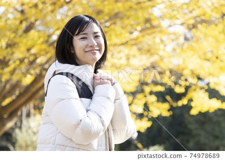A woman smiling looking at the camera in an autumn park 74978689
