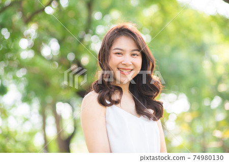 Asian beautiful women smiling in city public park morning light Asian beautiful women smiling in city public park morning light 74980130