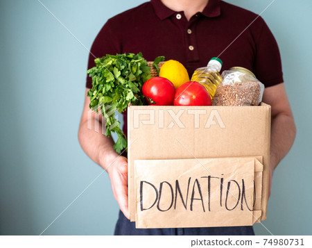 Man keeps donation box with goods in his hands, neighbourhood help concept Man keeps donation box with goods in his hands, neighbourhood help concept 74980731
