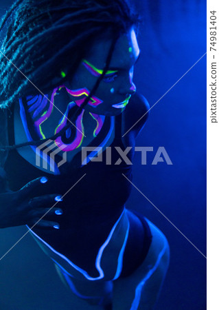 Cocky Girl with Dreadlocks in Ultraviolet neon light with Foggy Background. Bodyart 74981404