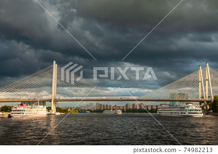 Russia. Saint-Petersburg. July 5, 2015. Bolshoy Obukhov bridge over the Neva River and pleasure boats on it in cloudy weather. View from the river. Russia. Saint-Petersburg. July 5, 2015. Bolshoy Obukhov bridge over the Neva River and pleasure boats on it in cloudy weather. View from the river. 74982213