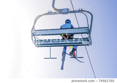 Ski lift on the slop in mountain ski resort with skier on the lift. Cableway for tourists, skiers and snowboarders. active rest in the mountains in winter.  74982768