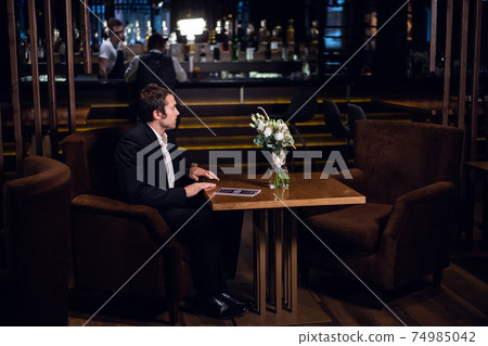 a single man in a jacket sits at a table in a restaurant after work a single man in a jacket sits at a table in a restaurant after work 74985042