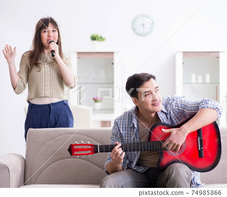 Young family singing and playing music at home 74985866