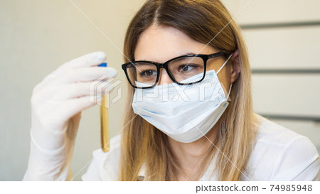 A woman holds a test tube with a urine test. Diagnostics and analysis concept 74985948