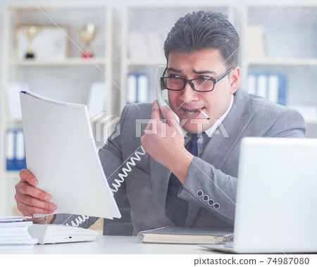 Businessman smoking in office at work Businessman smoking in office at work 74987080