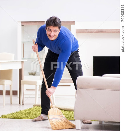Young man cleaning floor with broom Young man cleaning floor with broom 74988351