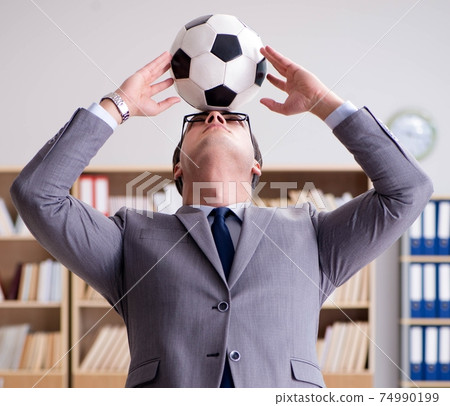 Businessman with football ball in office Businessman with football ball in office 74990199