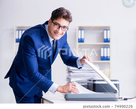 Businessman making copies in copying machine 74990226