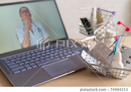 Online medicine and pharmacy concept. A female doctor conducts an online consultation and recommends medications. Mini trolley with tablets at the laptop. Online medicine and pharmacy concept. A female doctor conducts an online consultation and recommends medications. Mini trolley with tablets at the laptop. 74994313