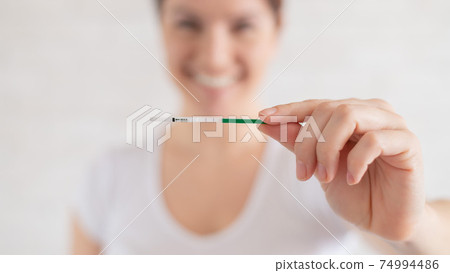 Happy woman shows a positive pregnancy test. The concept of female fertility. Human chorionic gonadotropin. Two stripes expecting a baby. Happy woman shows a positive pregnancy test. The concept of female fertility. Human chorionic gonadotropin. Two stripes expecting a baby. 74994486
