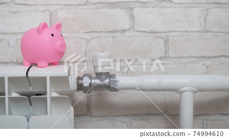 A piggy bank piggy bank on a radiator on a brick wall background 74994610
