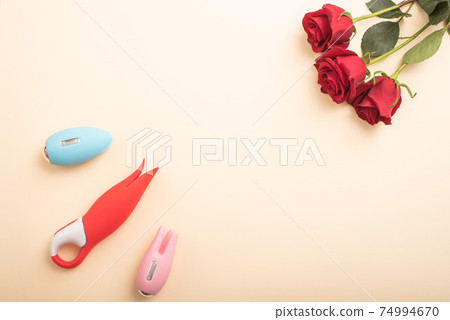 Flat lay from female masturbation accessories. Vibrators and roses on a peach background. Copy space Flat lay from female masturbation accessories. Vibrators and roses on a peach background. Copy space 74994670