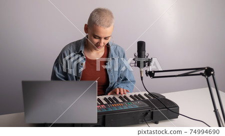 Young woman is broadcasting while playing the electric piano on a white background Young woman is broadcasting while playing the electric piano on a white background 74994690