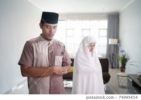 asian muslim praying by fold arm in front of a chest 74995654