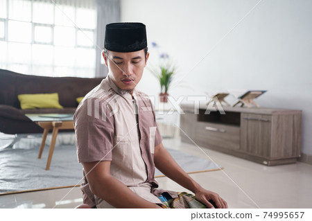 Young Muslim man praying at home 74995657