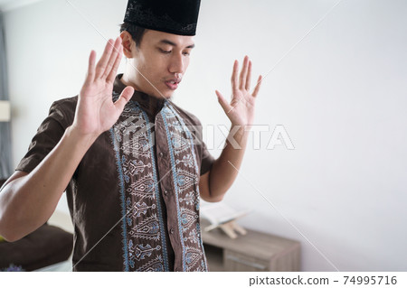 Young Muslim man praying at home Young Muslim man praying at home 74995716