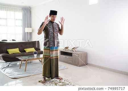 Young Muslim man praying at home Young Muslim man praying at home 74995717